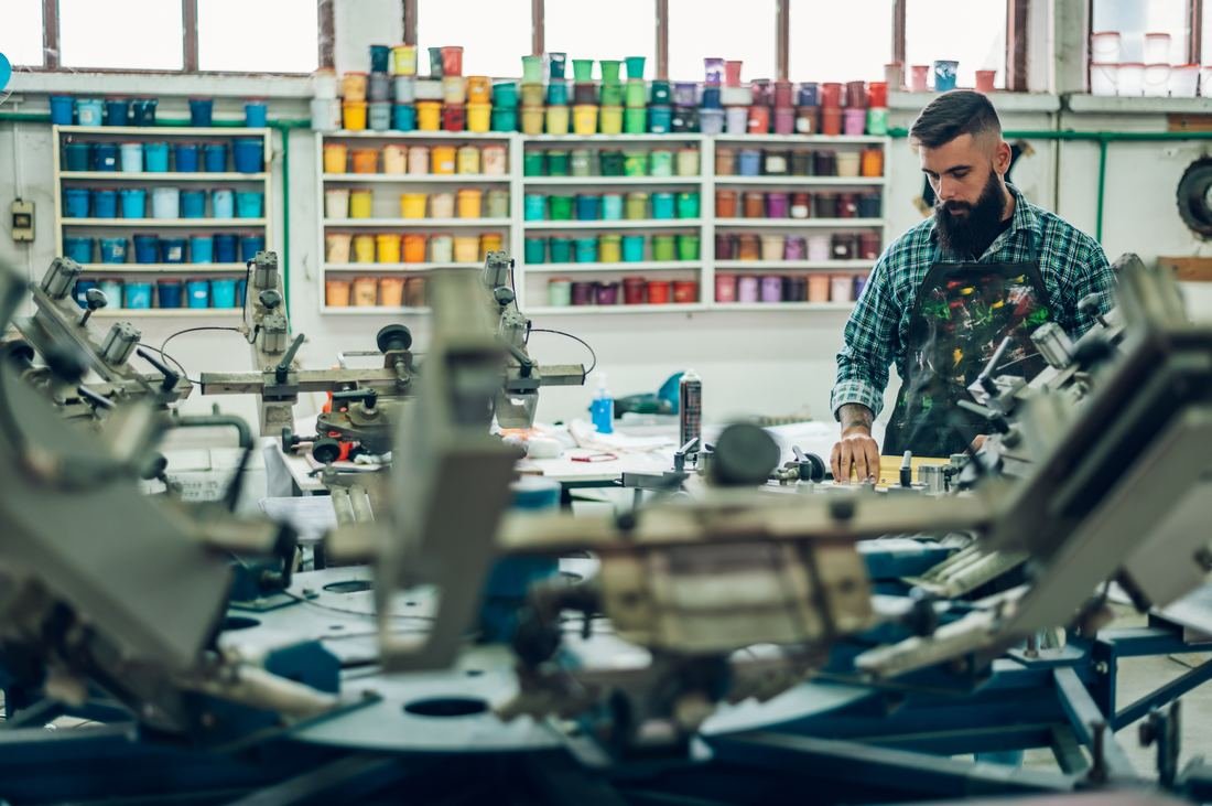 Shelves of colorful screen printing ink jars in a print shop, background layer